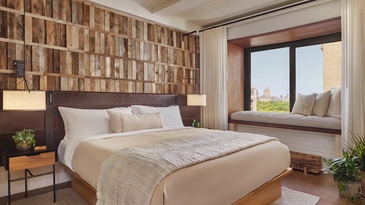 A guest room with a reclaimed-wood headboard wall and a window seat over Central Park