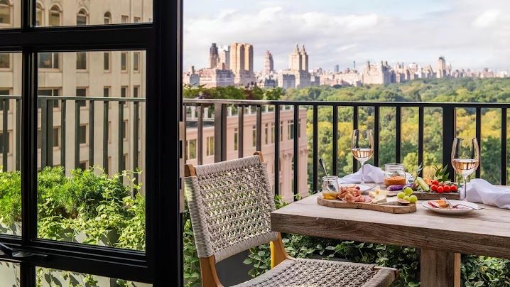 A private terrace set with wine and charcuterie, looking across Central Park's treetops to the skyline