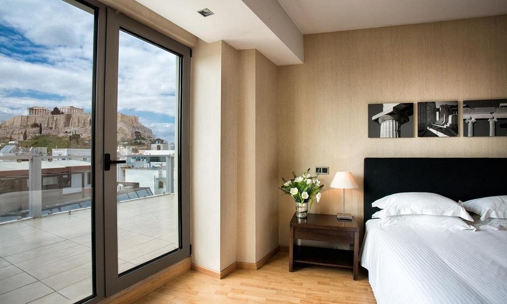 A guest room at The Athens Gate Hotel, with the Acropolis framed through the balcony door