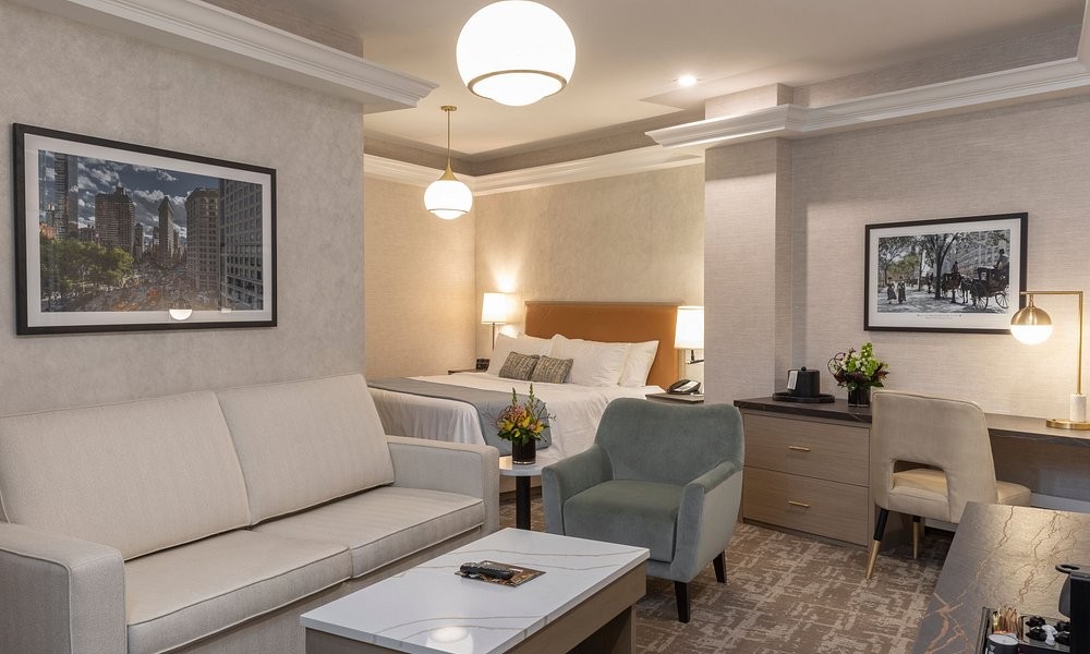 A guest room at Broadway Plaza Hotel, with an amber leather headboard and framed city photography