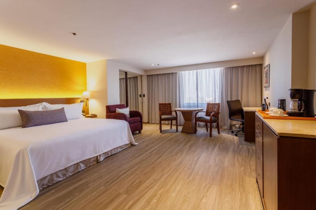 A guest room at Camino Real Aeropuerto, with a mustard accent wall