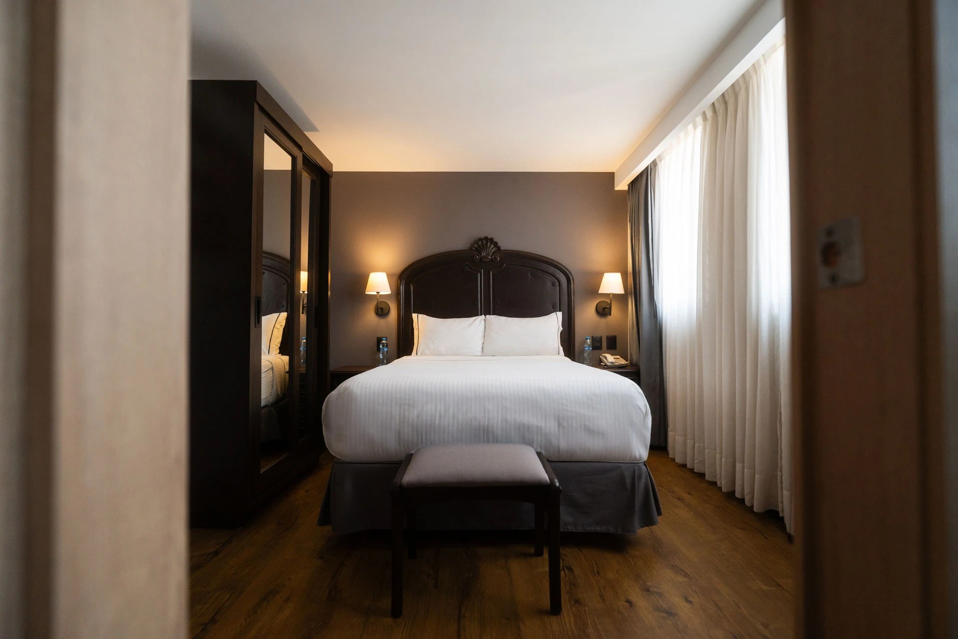 A guest room at Hotel Canada Central, with a carved wood headboard
