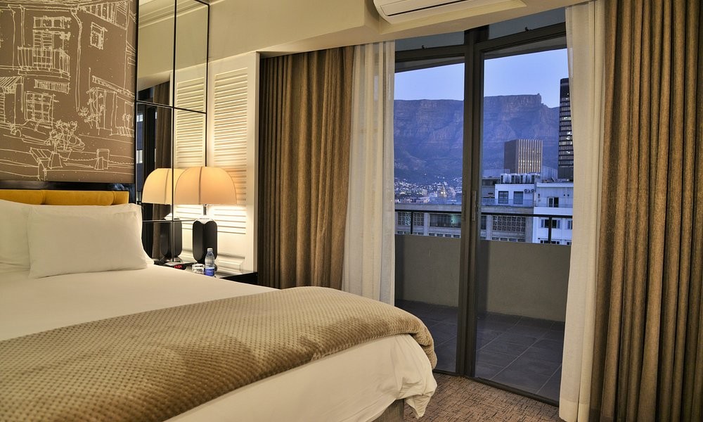 A guest room at The Capetonian, with Table Mountain framed through the balcony door at dusk