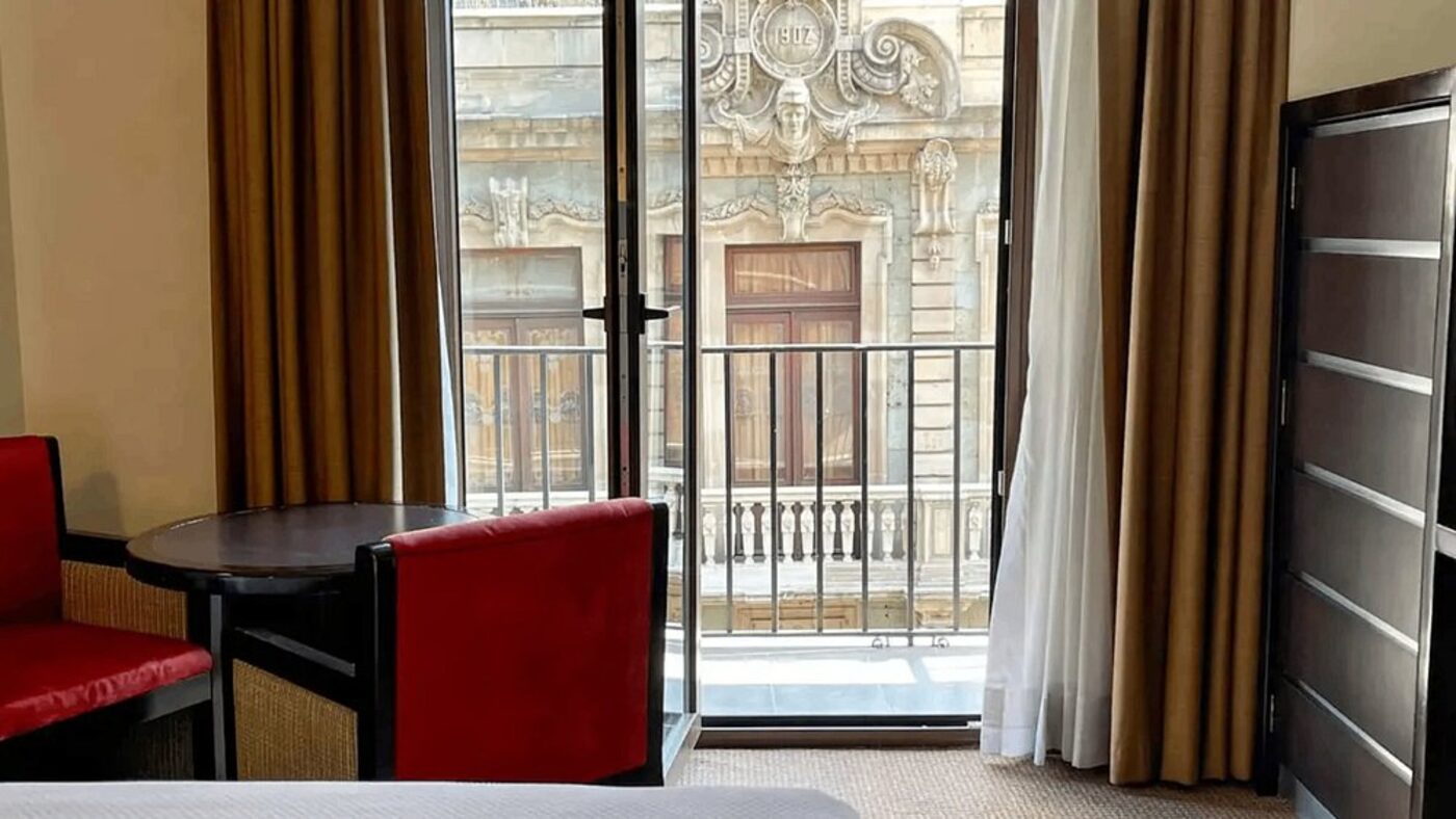 A room's Juliet balcony overlooking a carved historic facade in the Centro Histórico