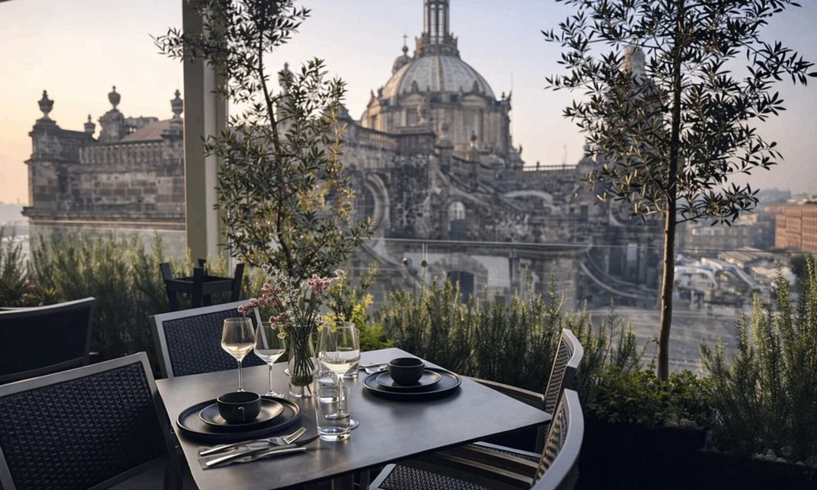 A table set for two on the rooftop terrace at Hotel Catedral, with the cathedral dome behind