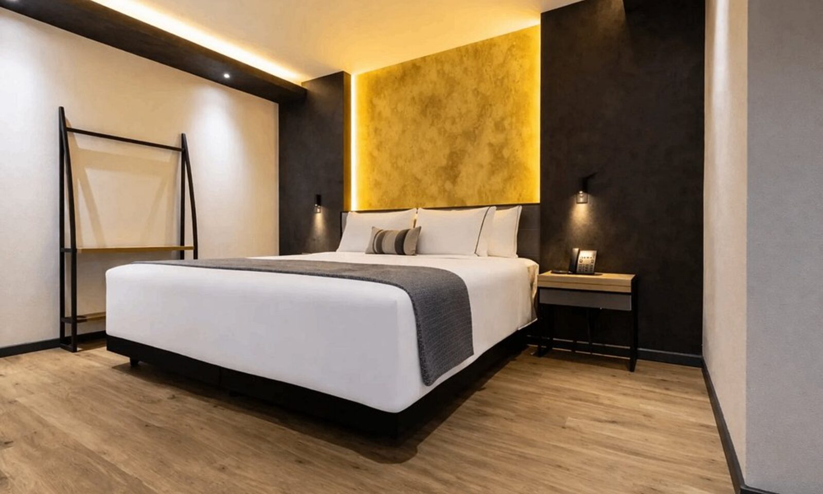 A guest room at Hotel Catedral with a backlit amber headboard and warm wood flooring