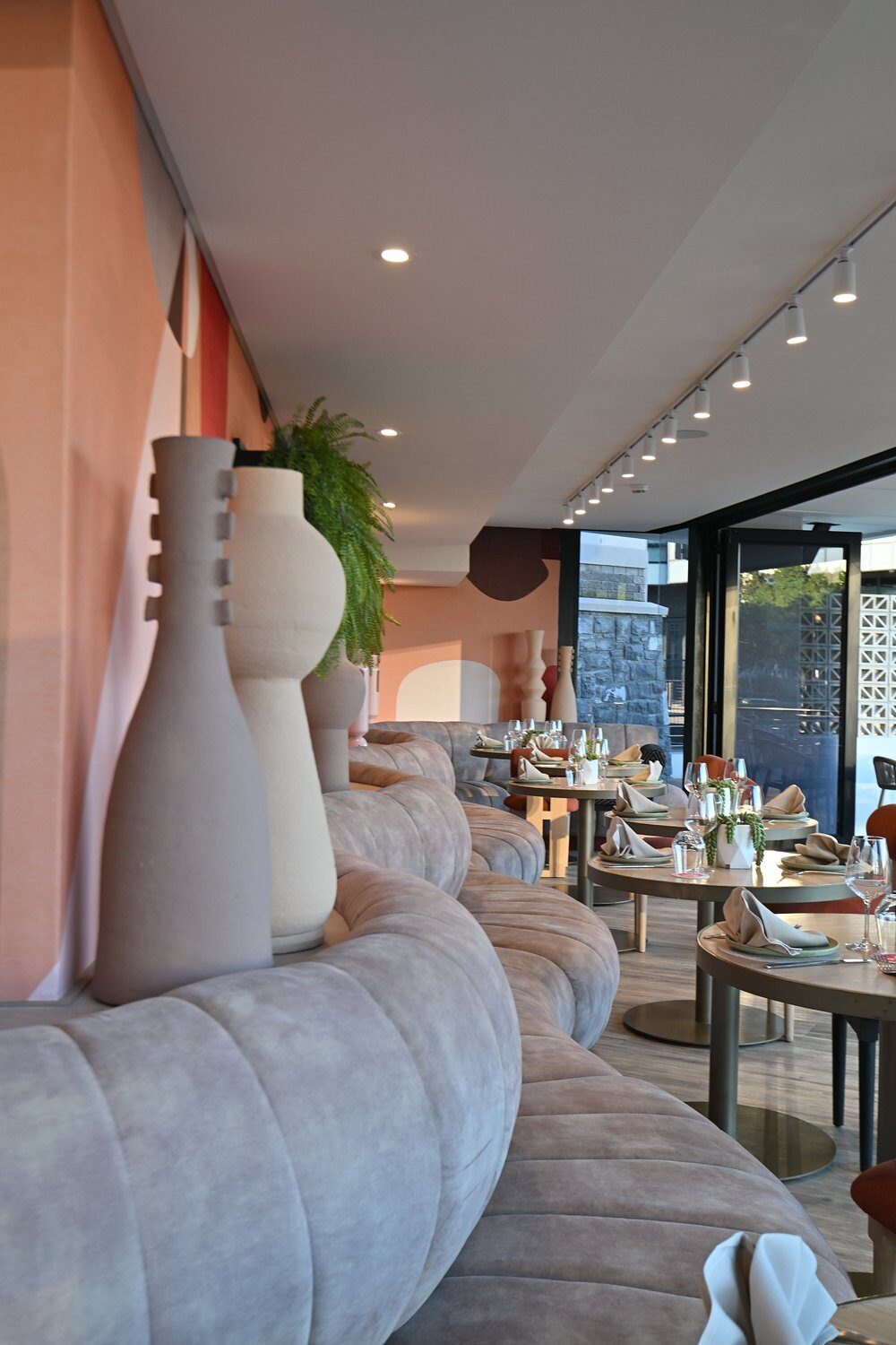A dining area with blush-pink walls and ceramic vases