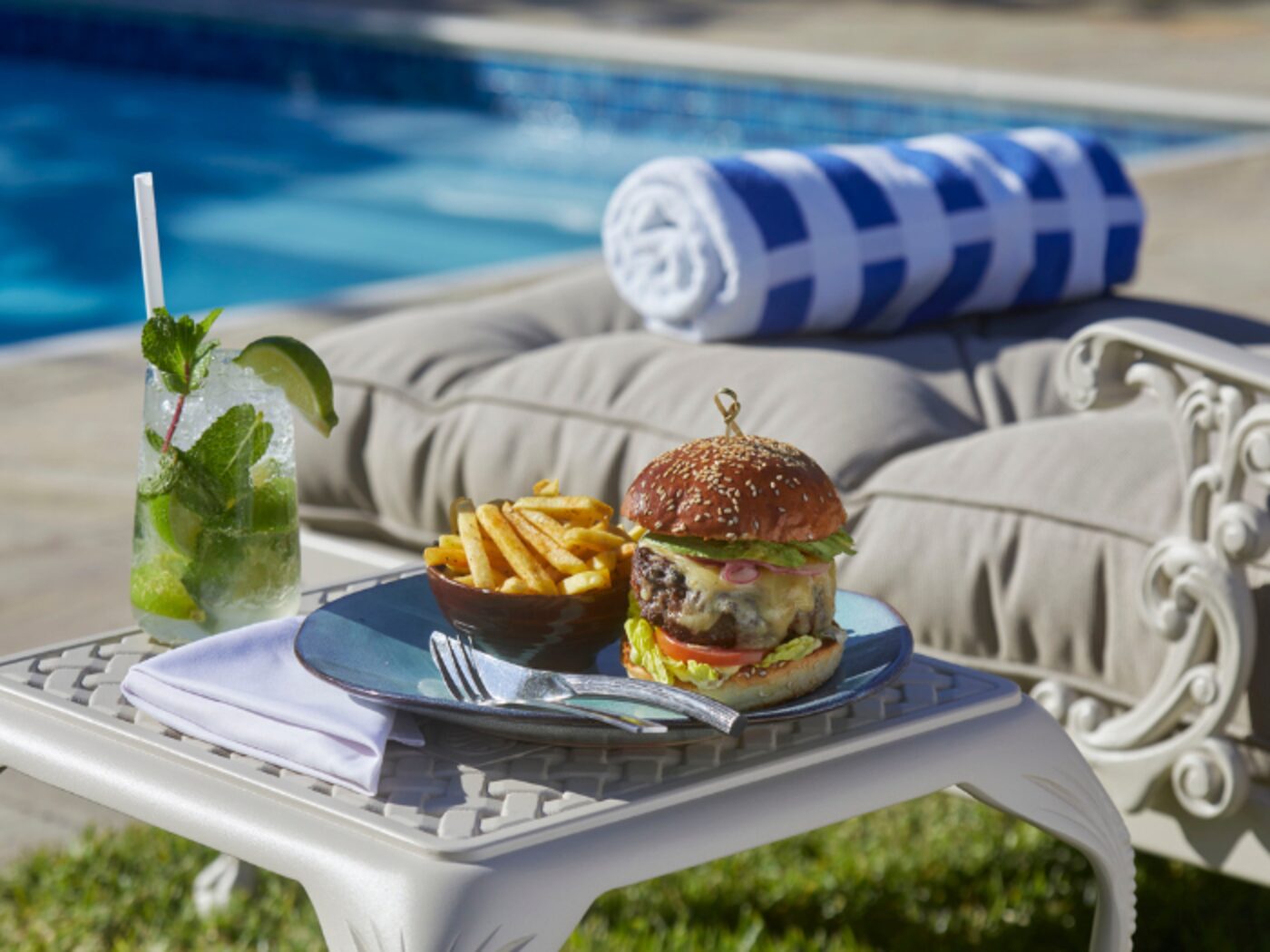 A burger and mojito served poolside