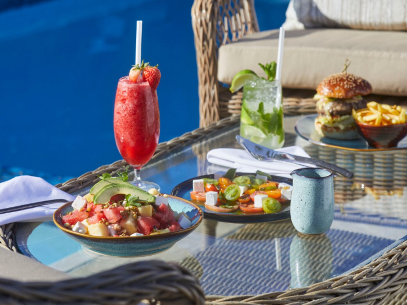 Poolside fare — a burger, salads and cocktails set beside the pool