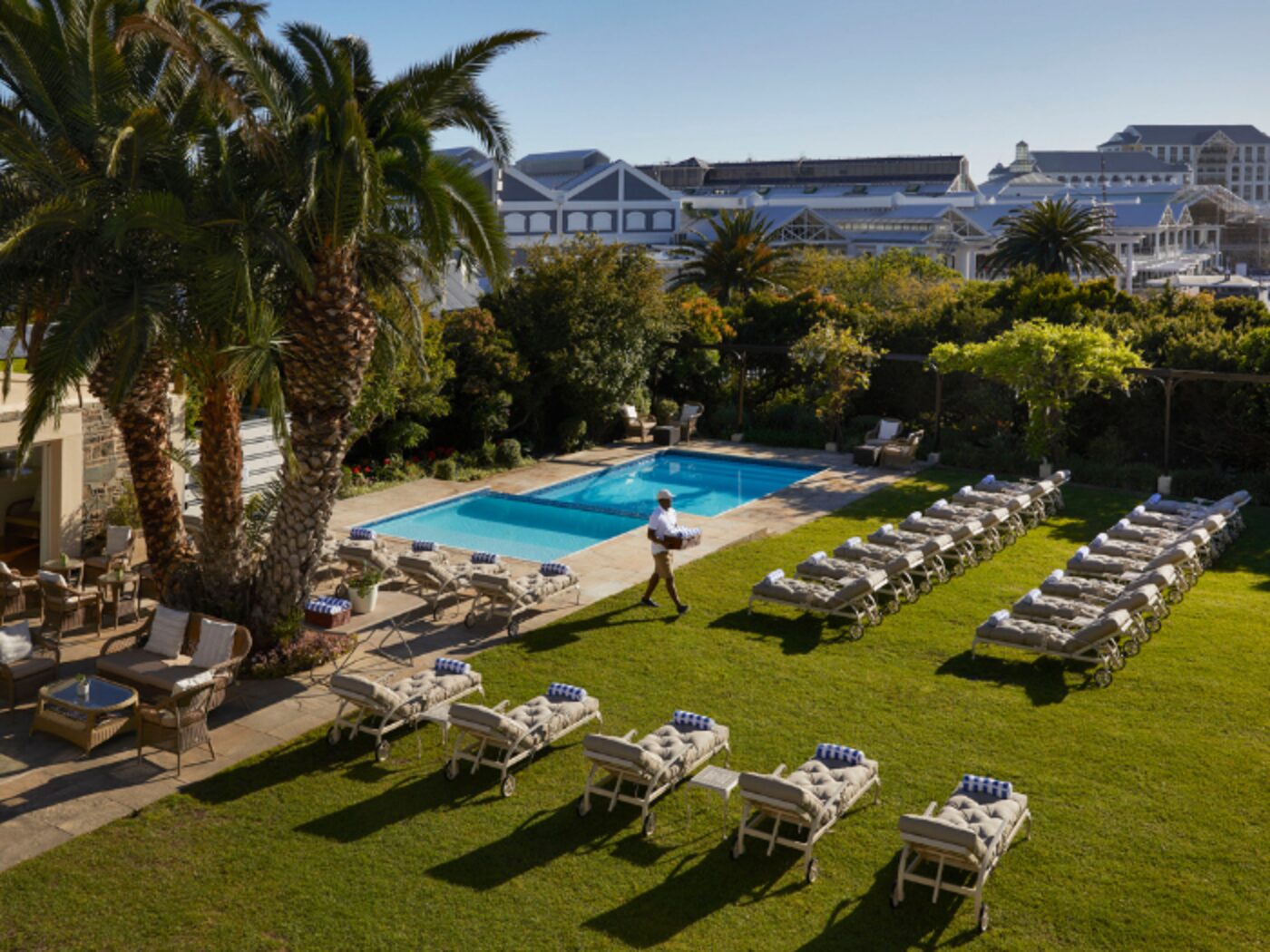 An aerial view of the lawn and pool, with staff bringing poolside service
