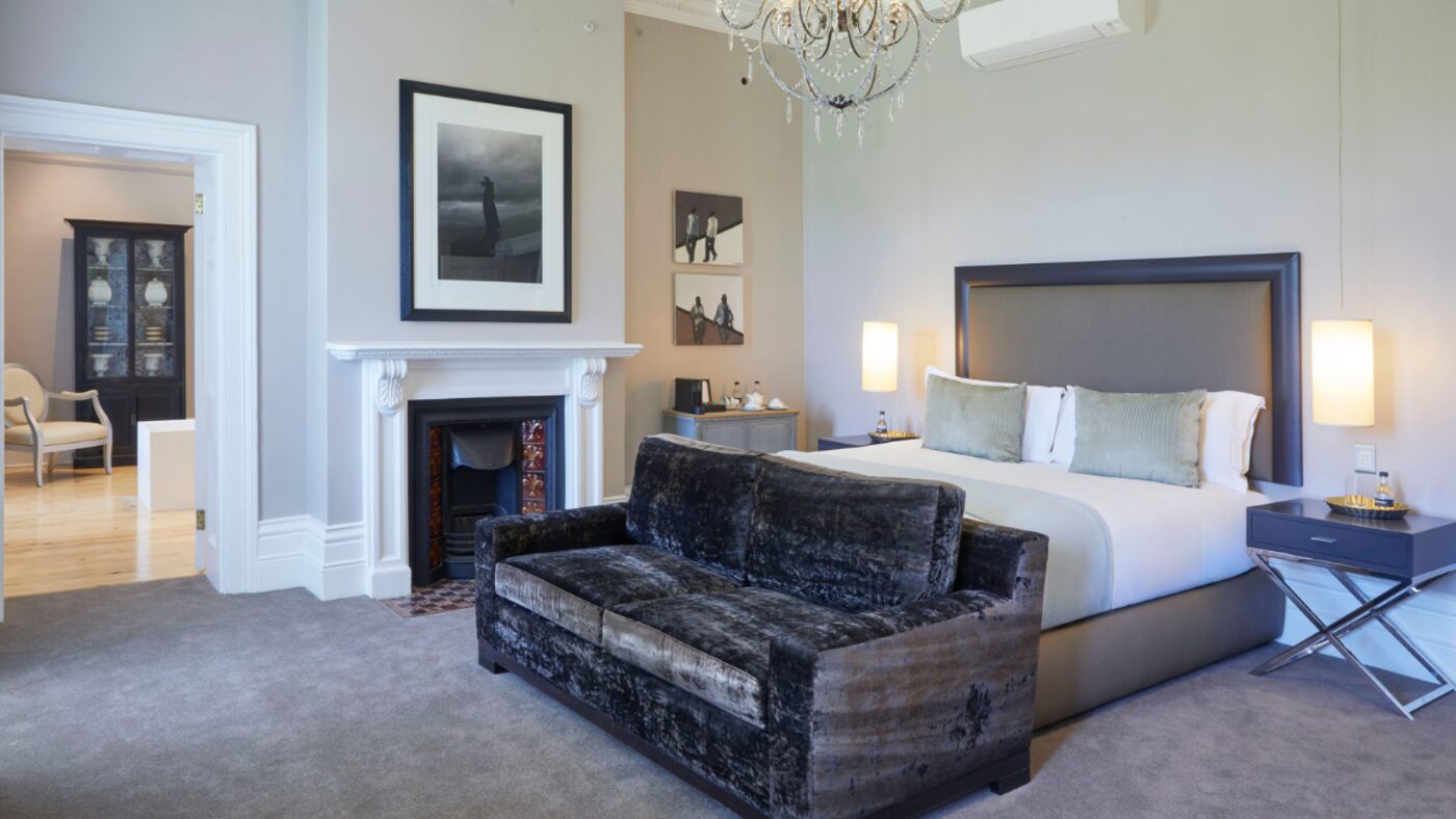 A suite bedroom with a dark velvet sofa and crystal chandelier