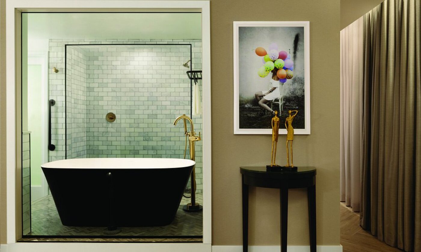 A bathroom with a black freestanding tub and marble-tiled shower