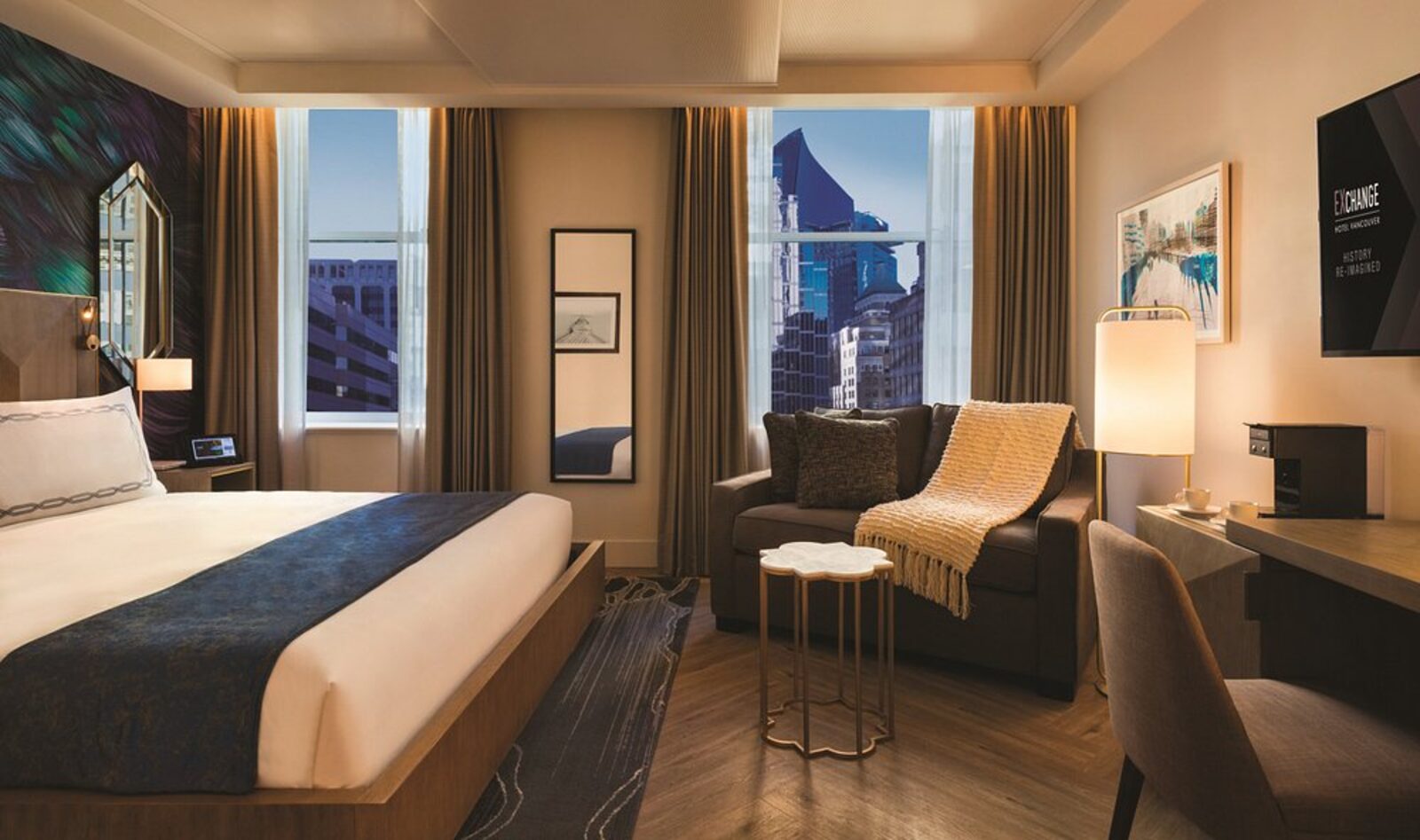 A room at Exchange Hotel Vancouver with a city view and the hotel's History Re-Imagined branding on screen