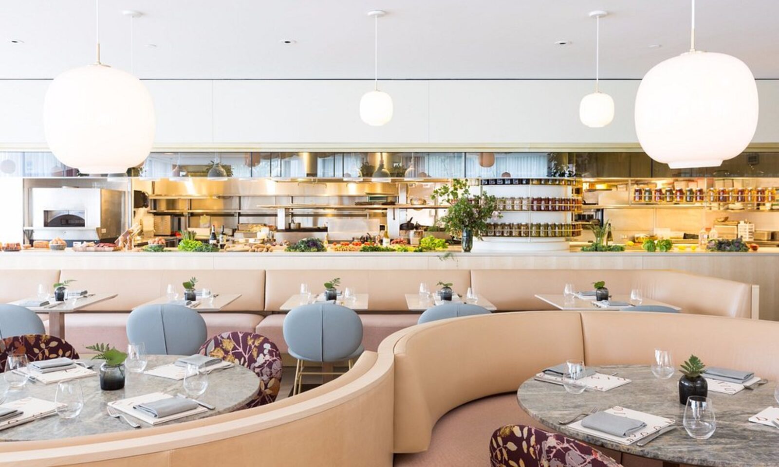 A hotel restaurant with a curved banquette and open kitchen