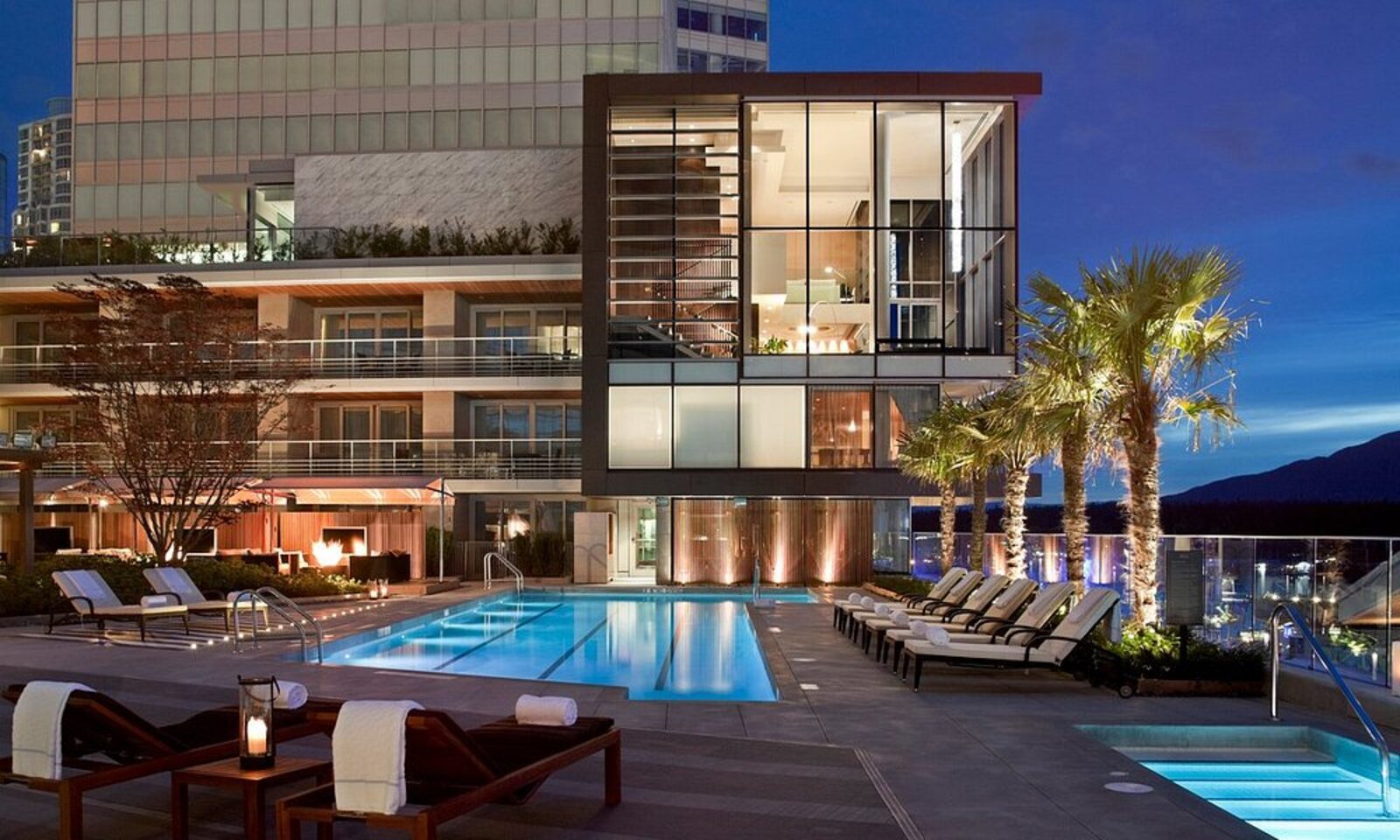 The rooftop pool at Fairmont Pacific Rim at dusk, with loungers and city lights beyond