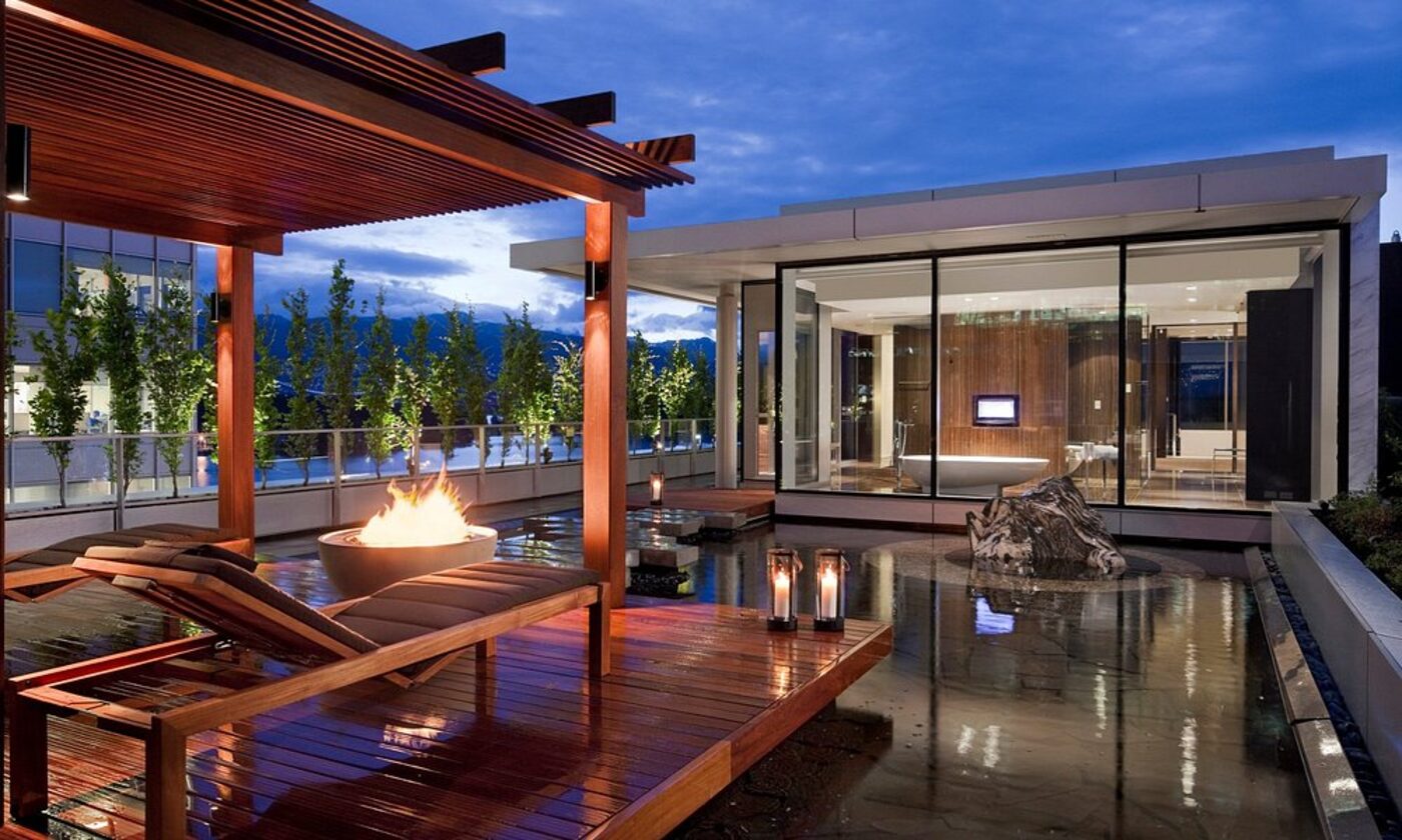 A rooftop spa terrace with a fire pit and soaking pool at dusk