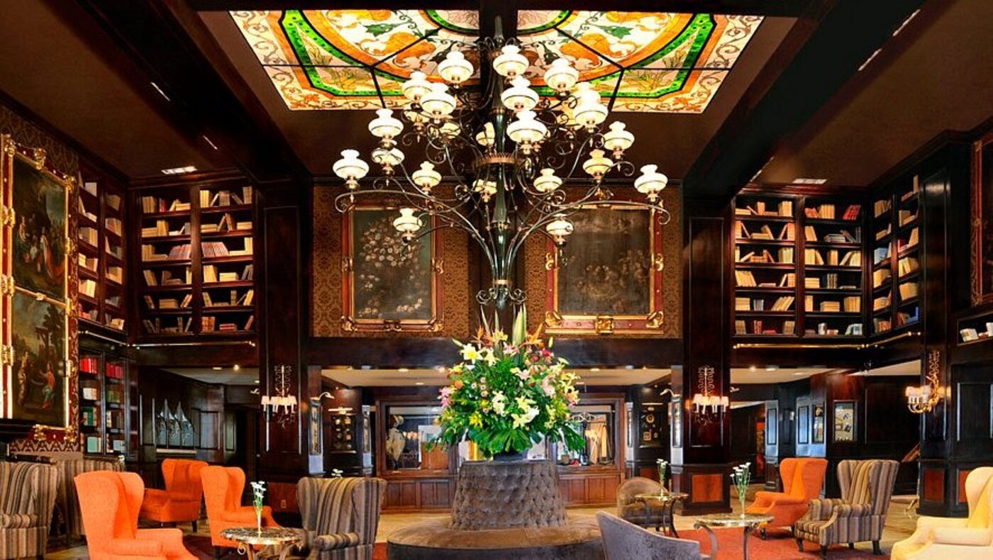 The hotel's library lobby, with a stained-glass ceiling and floor-to-ceiling bookshelves