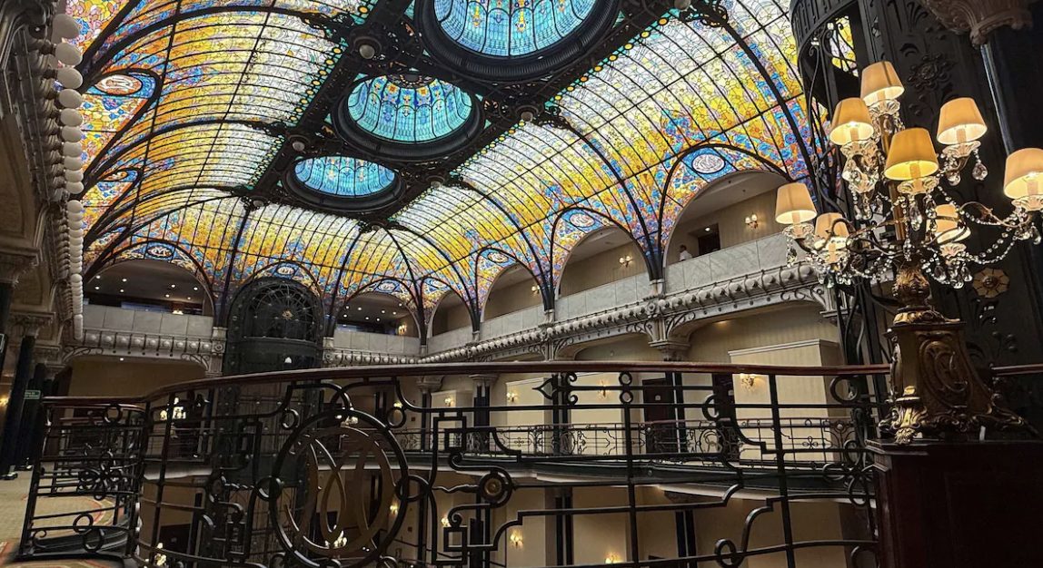 The atrium by evening, with its wrought-iron birdcage elevator and curving balconies