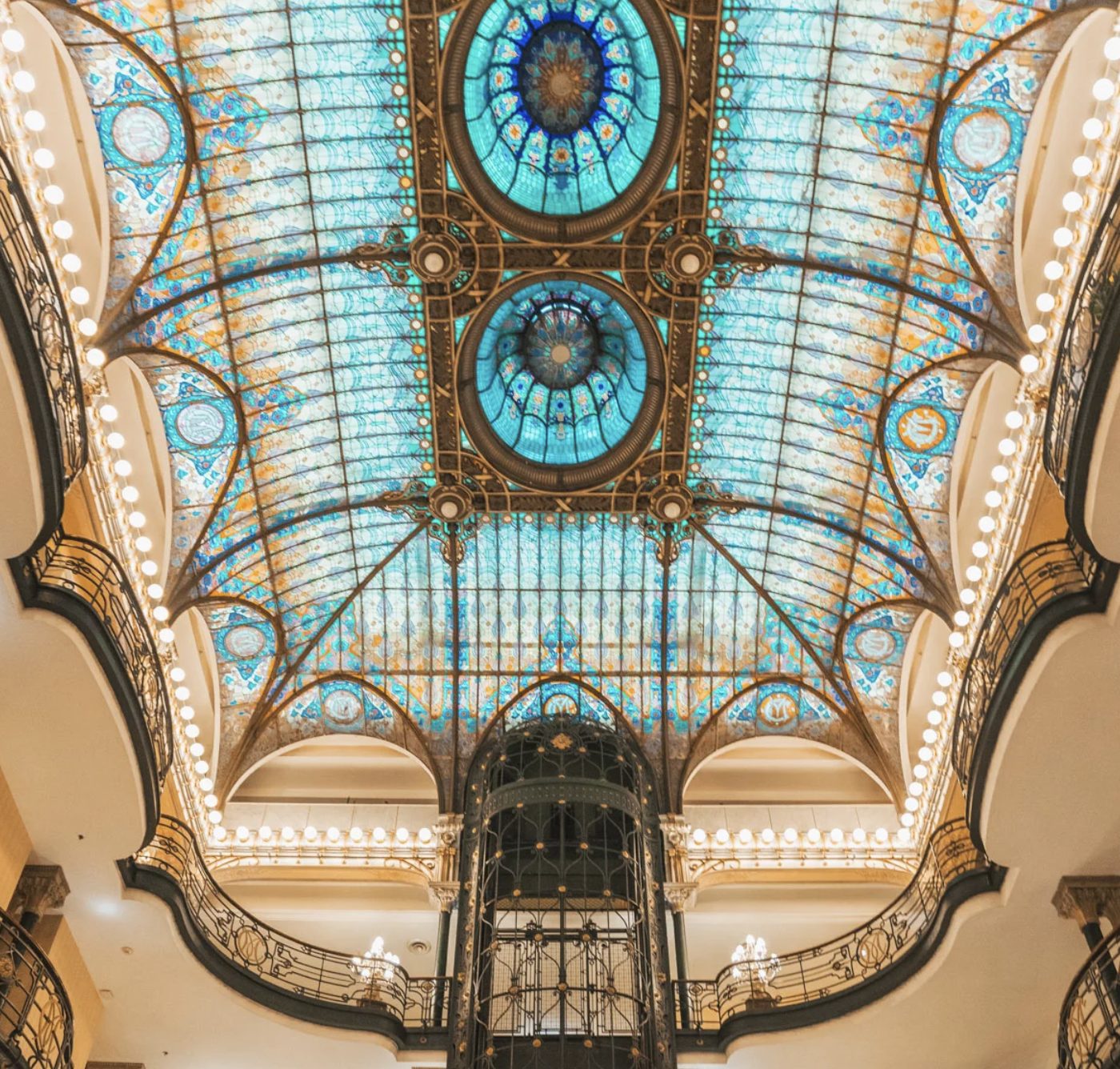 The luminous glass ceiling and birdcage elevator seen from below