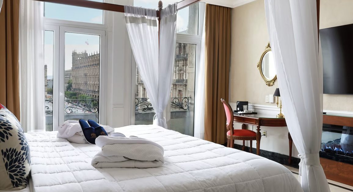 A guest room with a four-poster bed and a balcony over the Zócalo