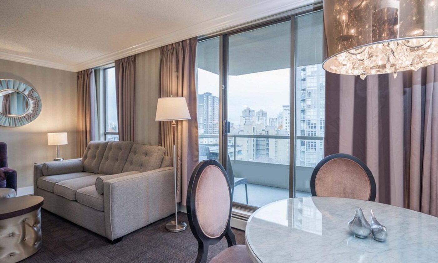 A suite living and dining area with balcony views over the city
