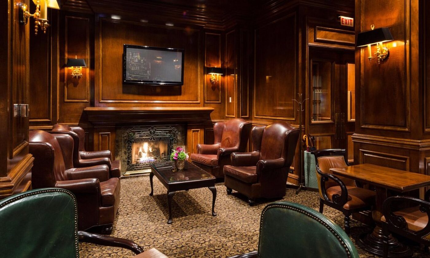 A wood-panelled lounge with leather armchairs and a fireplace