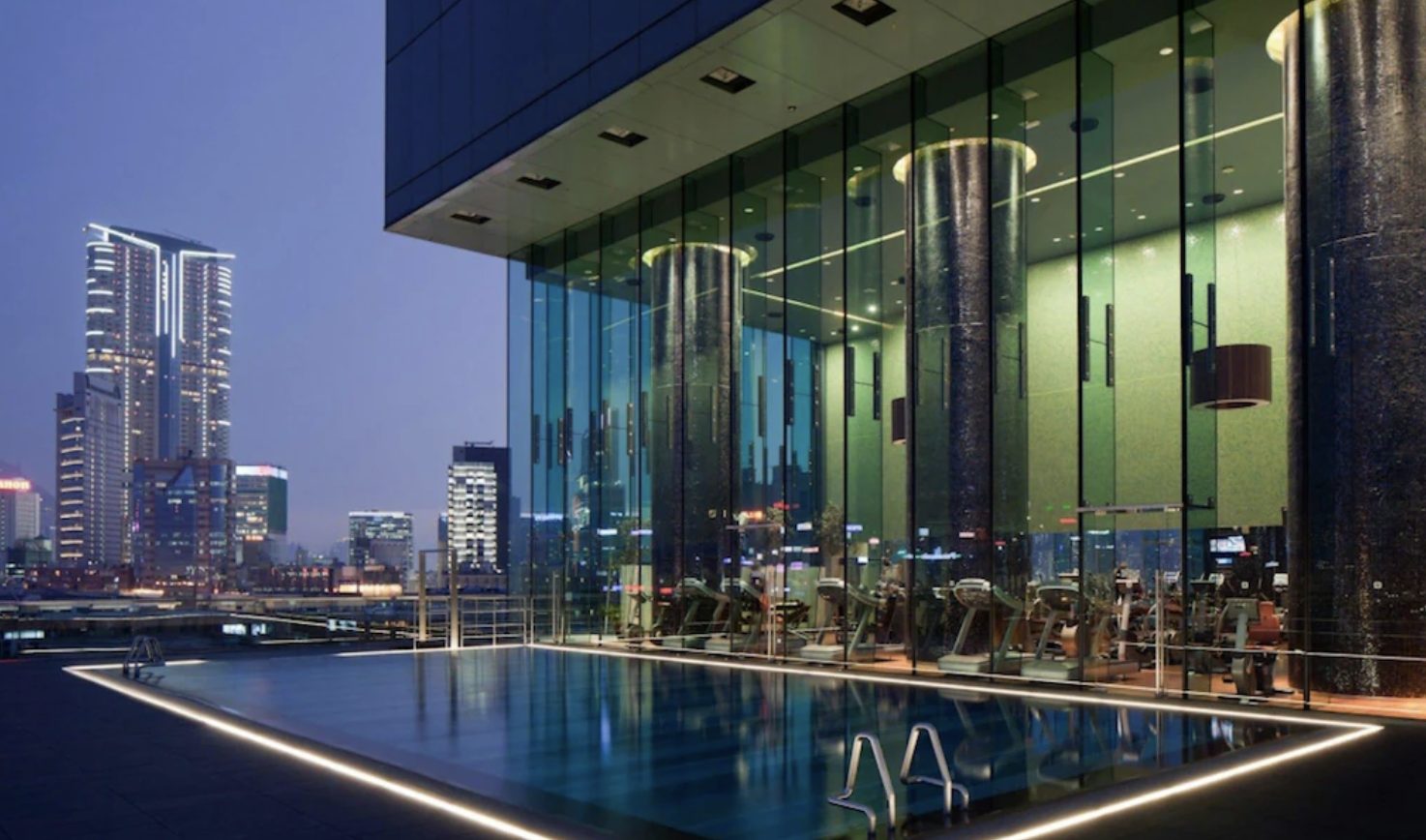 The rooftop pool at dusk, above the Kowloon skyline