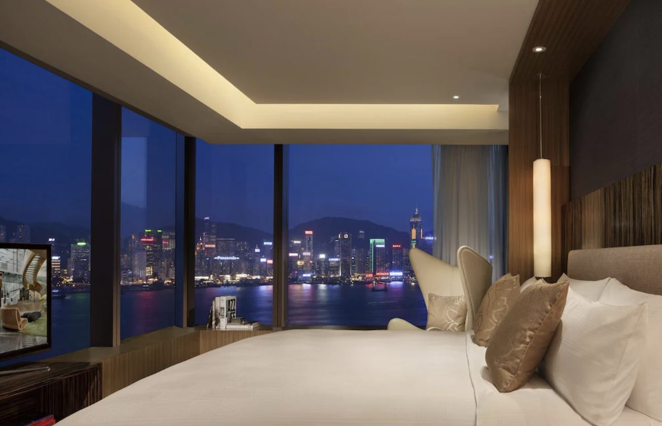 A guest room with floor-to-ceiling views over Victoria Harbour at night