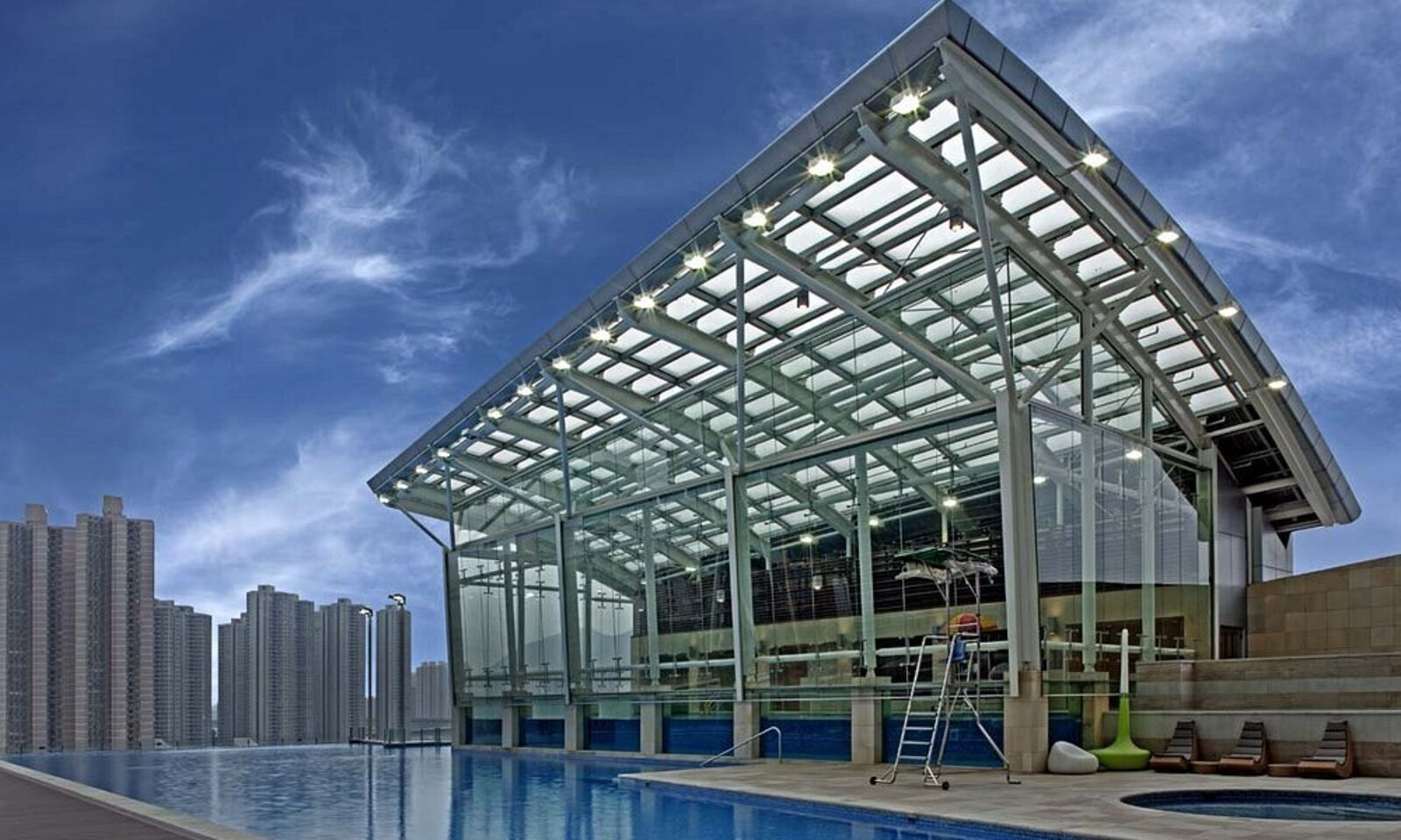 Nina Hotel Tsuen Wan West's outdoor pool deck overlooking the waterfront skyline