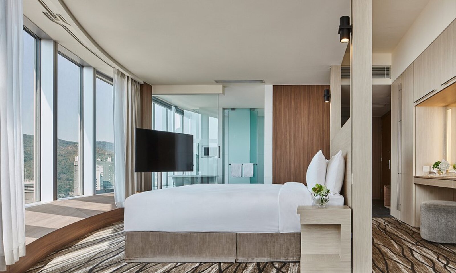 A spacious room at Nina Hotel Tsuen Wan West with floor-to-ceiling windows and a mountain view