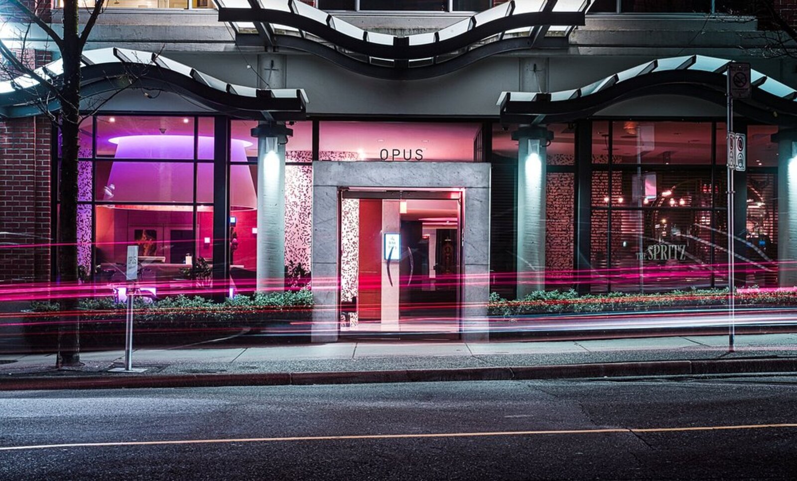 OPUS Vancouver's vividly lit entrance on a Yaletown street at night