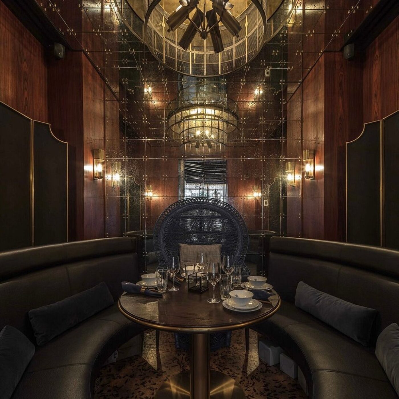 A plush, dark dining booth with brass and mirrored details