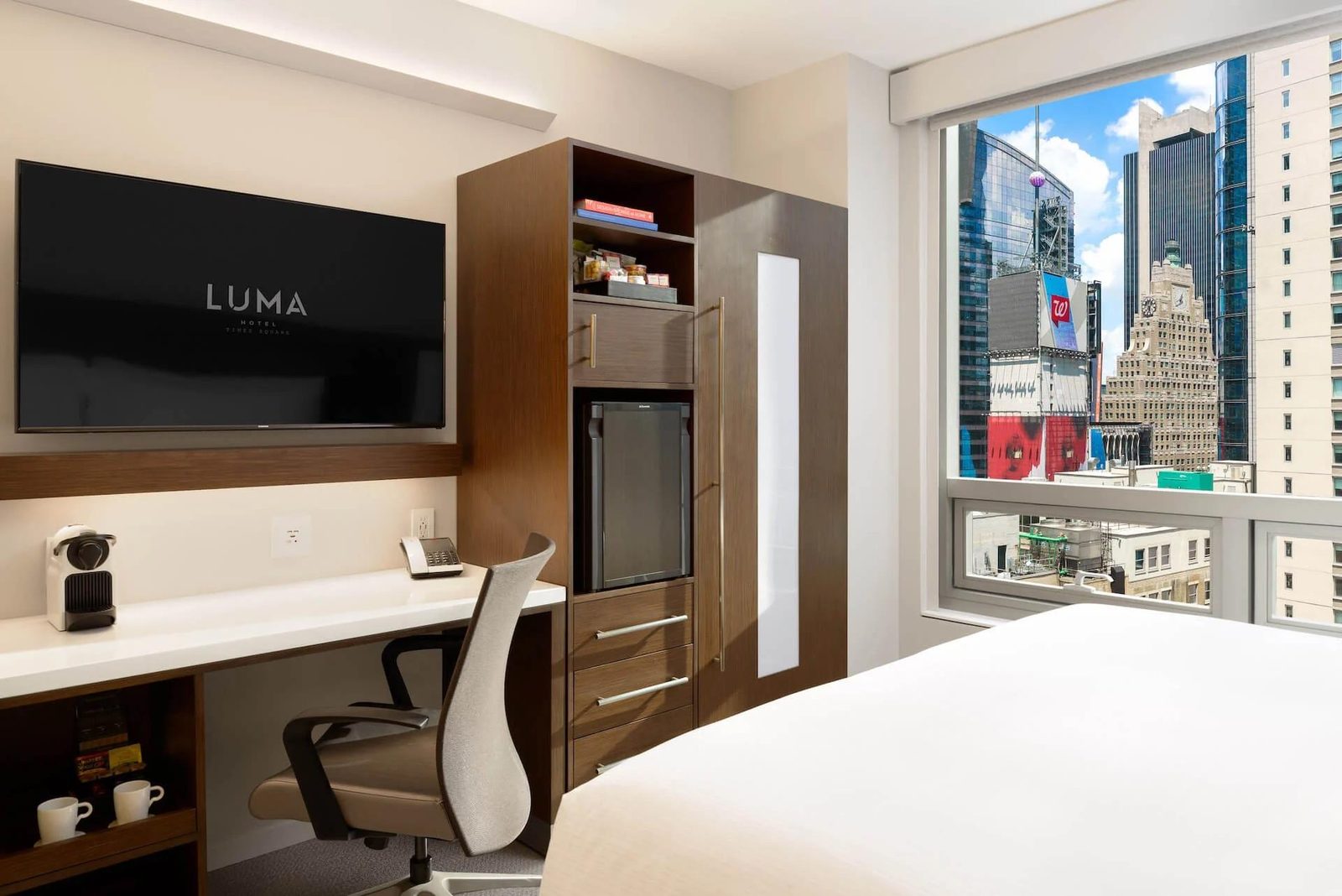 A guest room with walnut joinery and a window onto the Times Square skyline