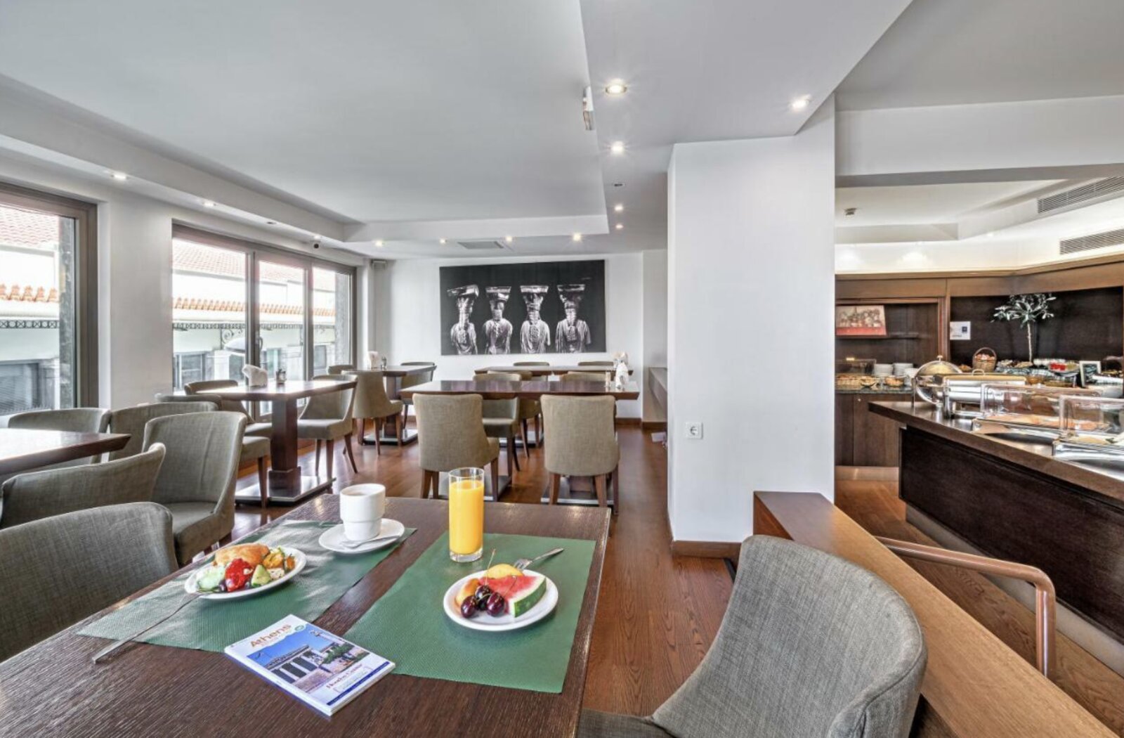 The breakfast lounge at Plaka Hotel with dining tables and a view onto the street