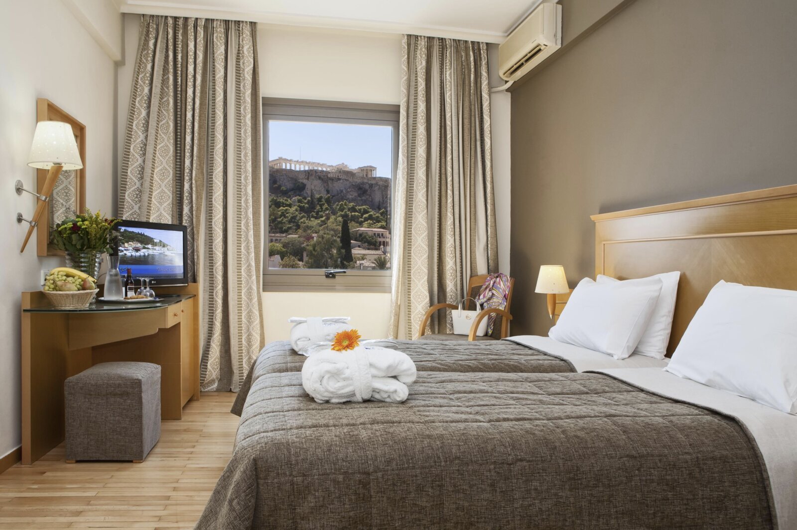 A twin room at Plaka Hotel with the Acropolis framed in the window beyond the rooftops