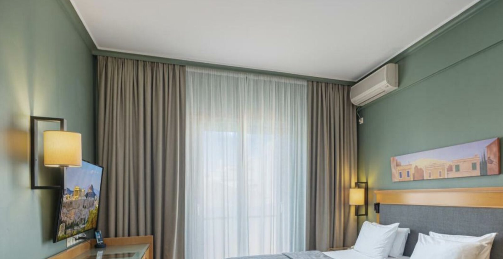 A calm, characterful room at Plaka Hotel with sage-green walls and local artwork