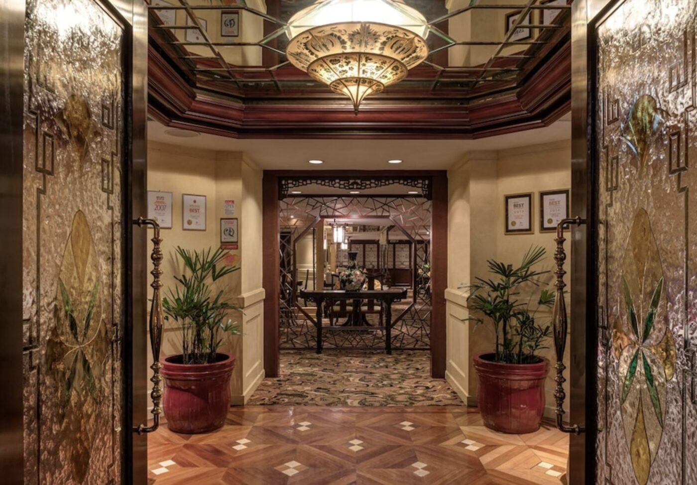 An ornate gilded entrance to one of the hotel's restaurants, flanked by potted palms