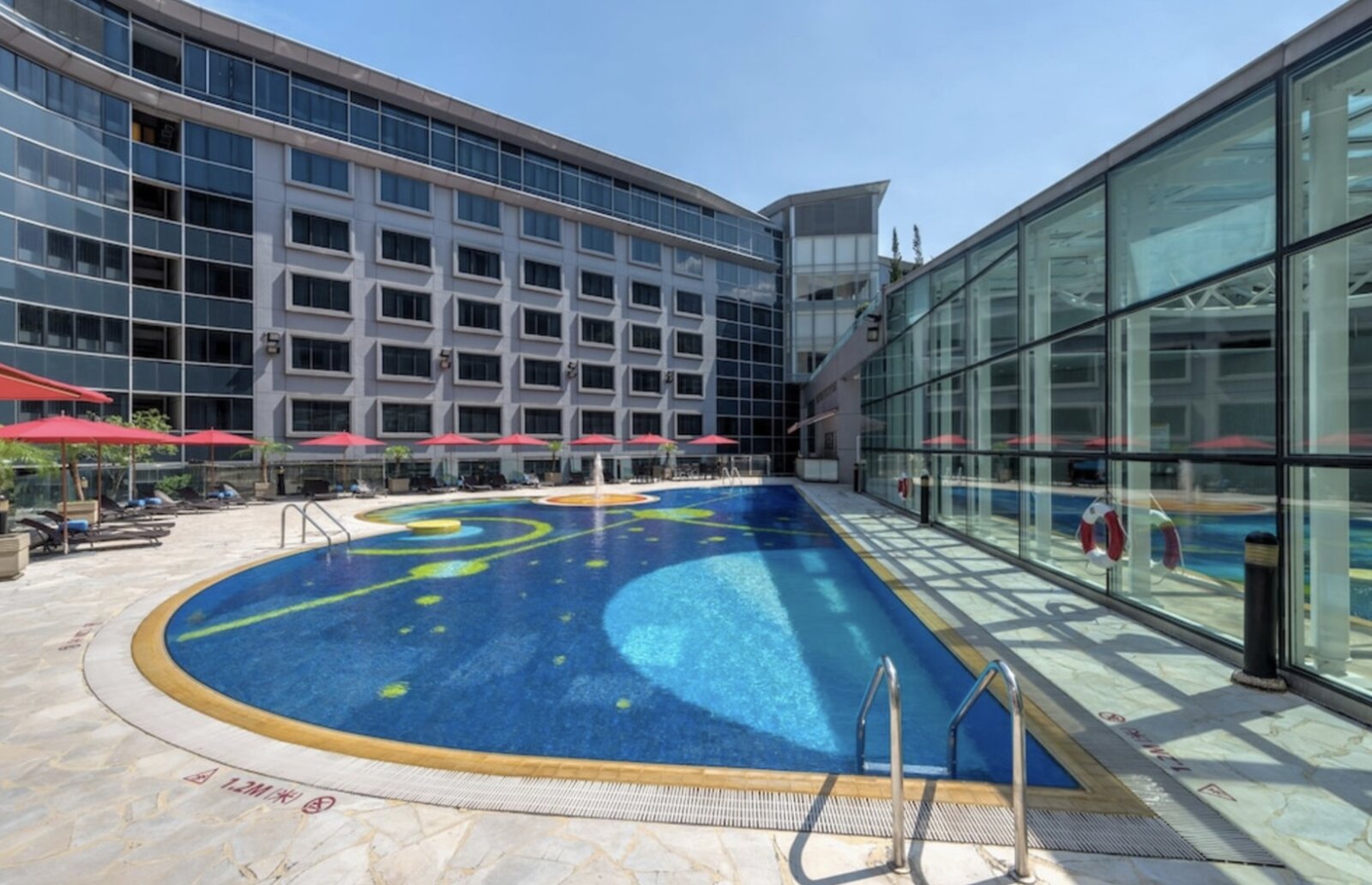 The outdoor pool and sun terrace at Regal Airport Hotel, framed by the hotel's own wings