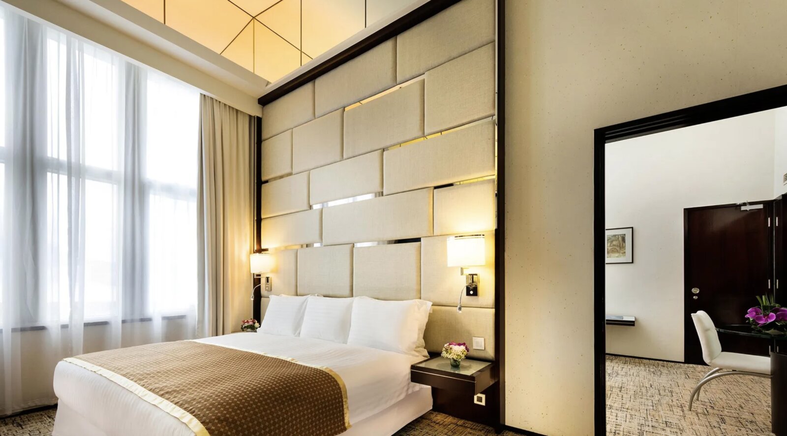 A calm, contemporary bedroom at Regal Airport Hotel with a tall upholstered headboard