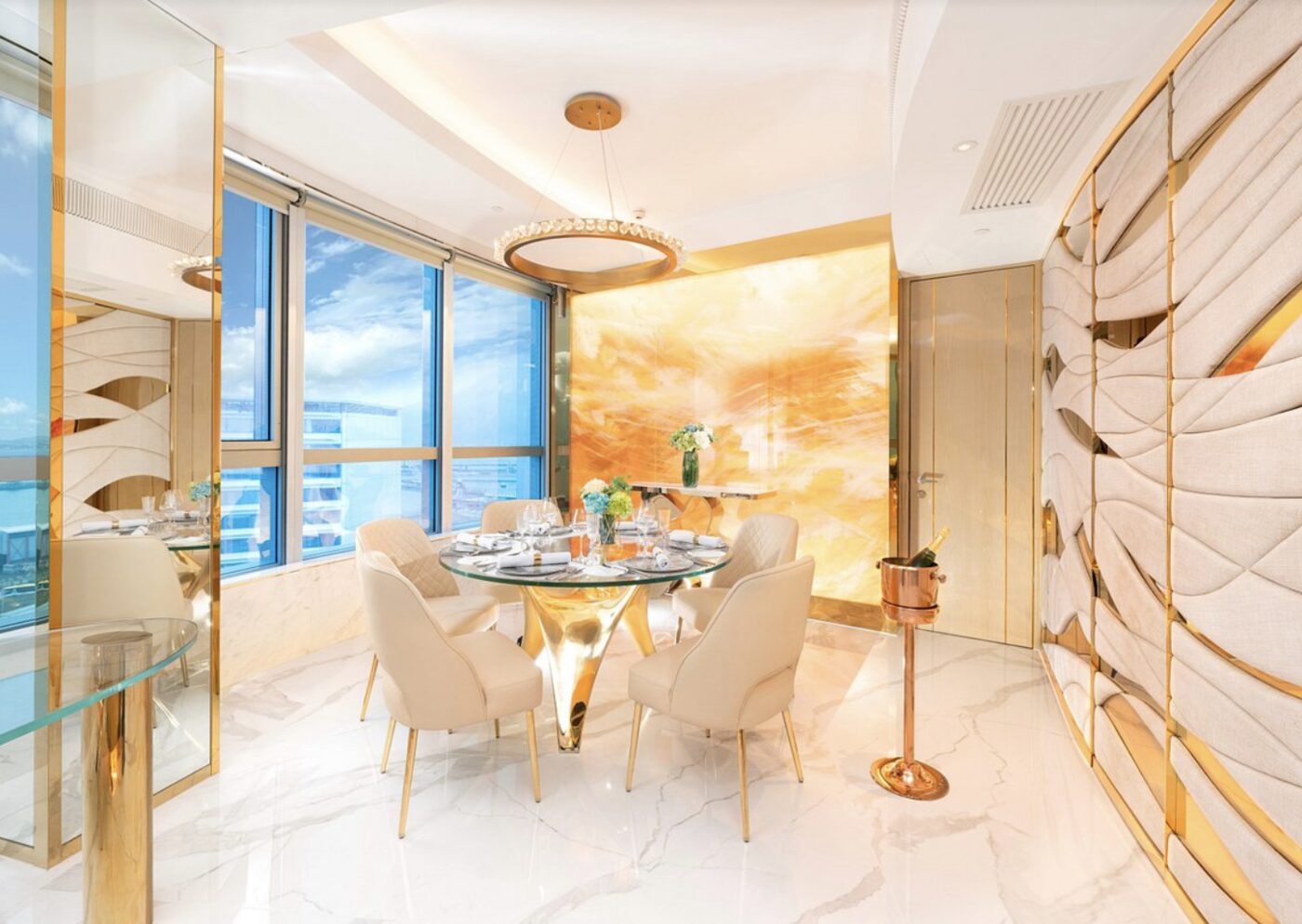 A private in-suite dining table set for four, with gold accents and a harbour view