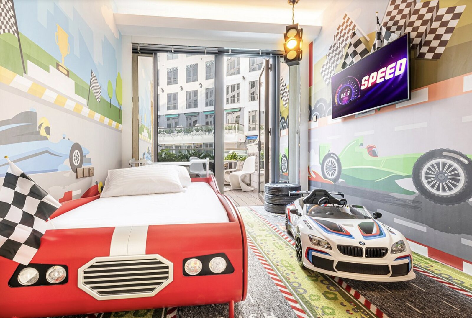 A race-car themed children's room at Regala Skycity Hotel, with a car-shaped bed and ride-on toy car