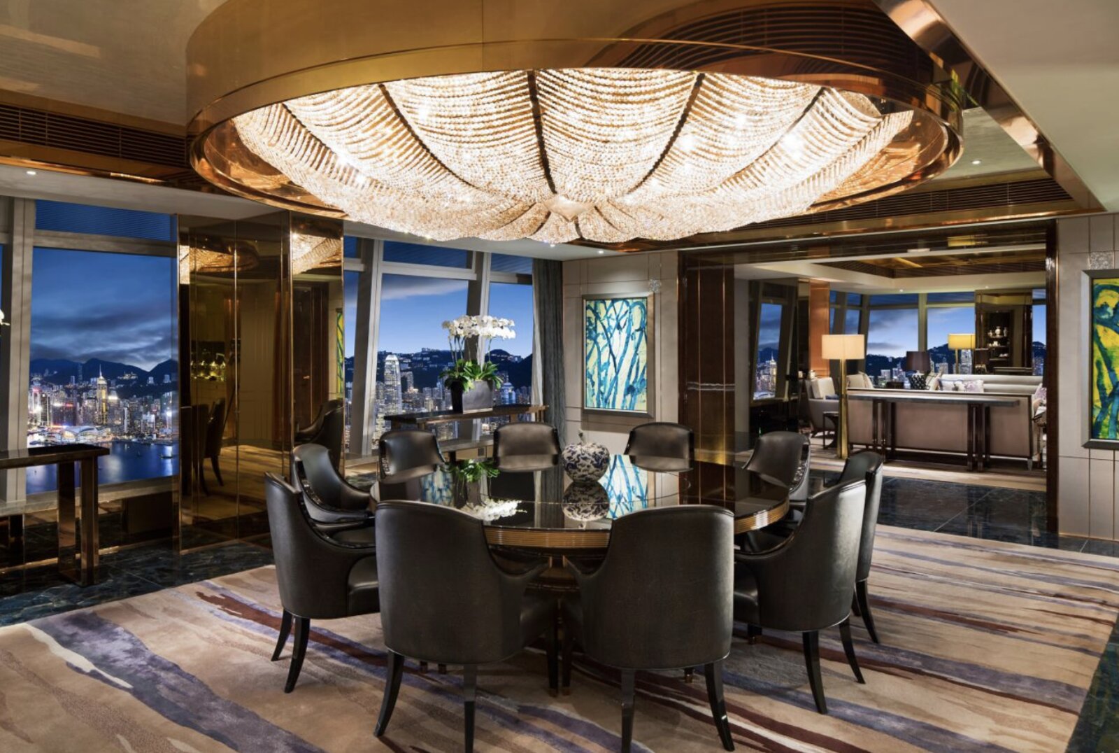 A private dining room in a suite at The Ritz-Carlton, Hong Kong, set beneath a large crystal chandelier with skyline views