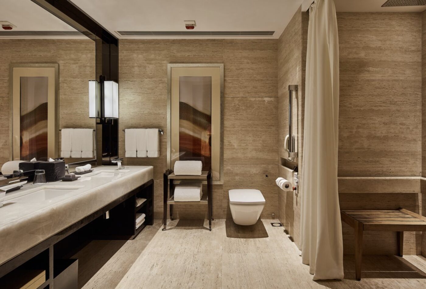 An accessible bathroom at The Ritz-Carlton, Hong Kong with grab rails and a roll-in shower
