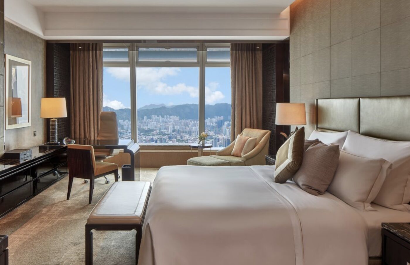A work desk beside floor-to-ceiling windows overlooking the mountains and city below