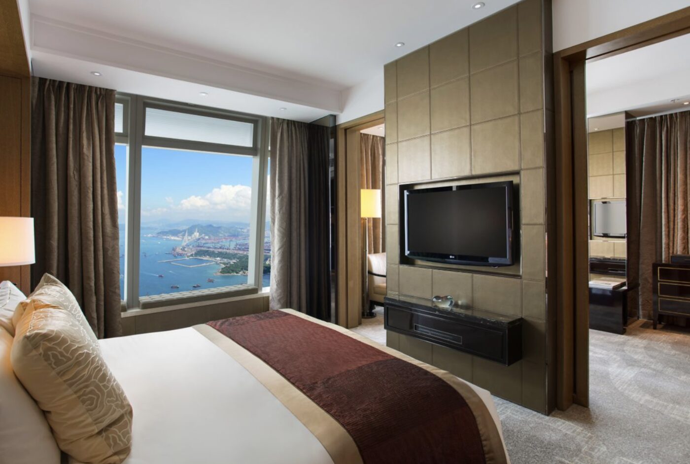 A bedroom at The Ritz-Carlton, Hong Kong with a wall-mounted television and views over the harbour