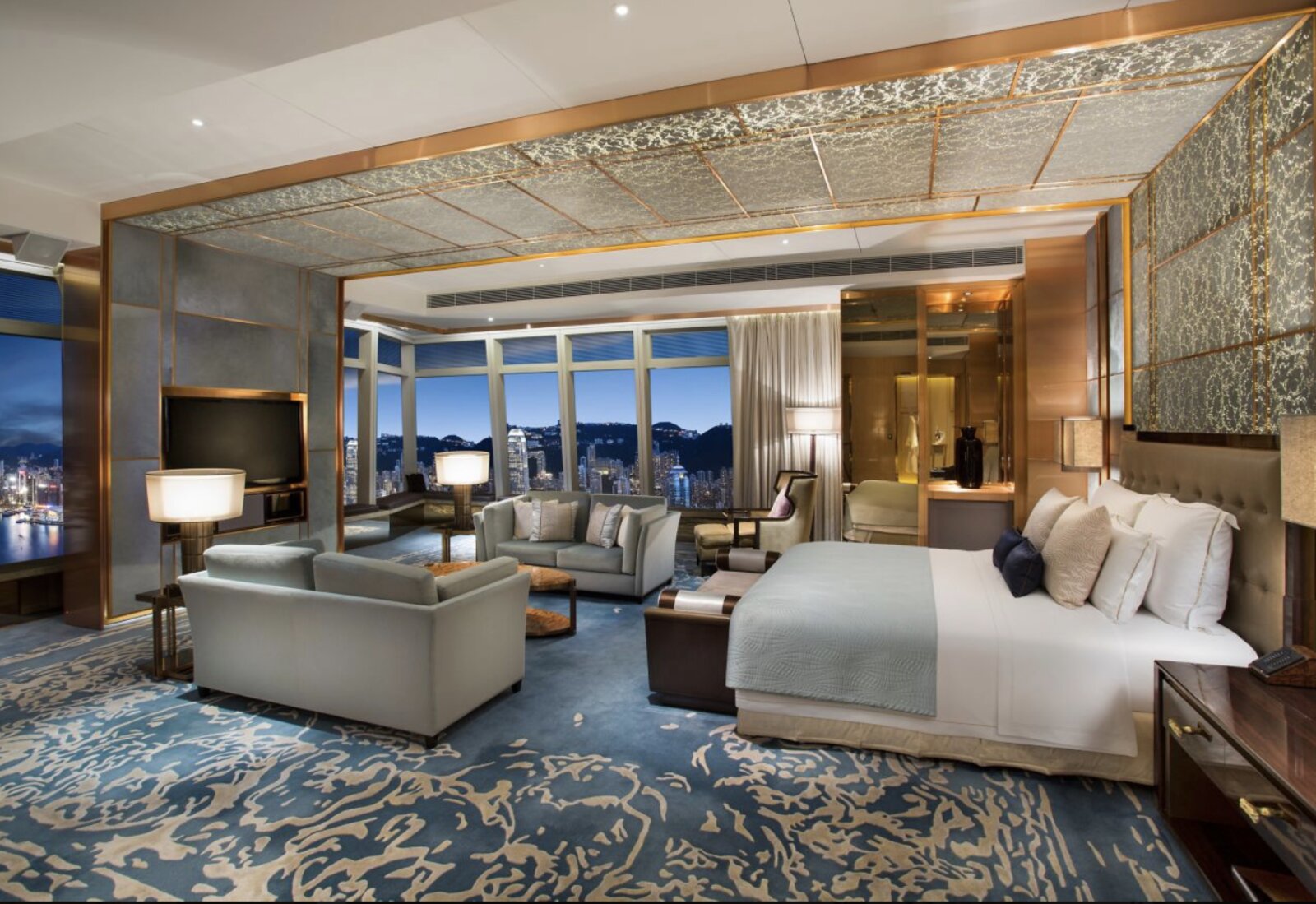 A suite at The Ritz-Carlton, Hong Kong with a blue patterned carpet and floor-to-ceiling harbour views