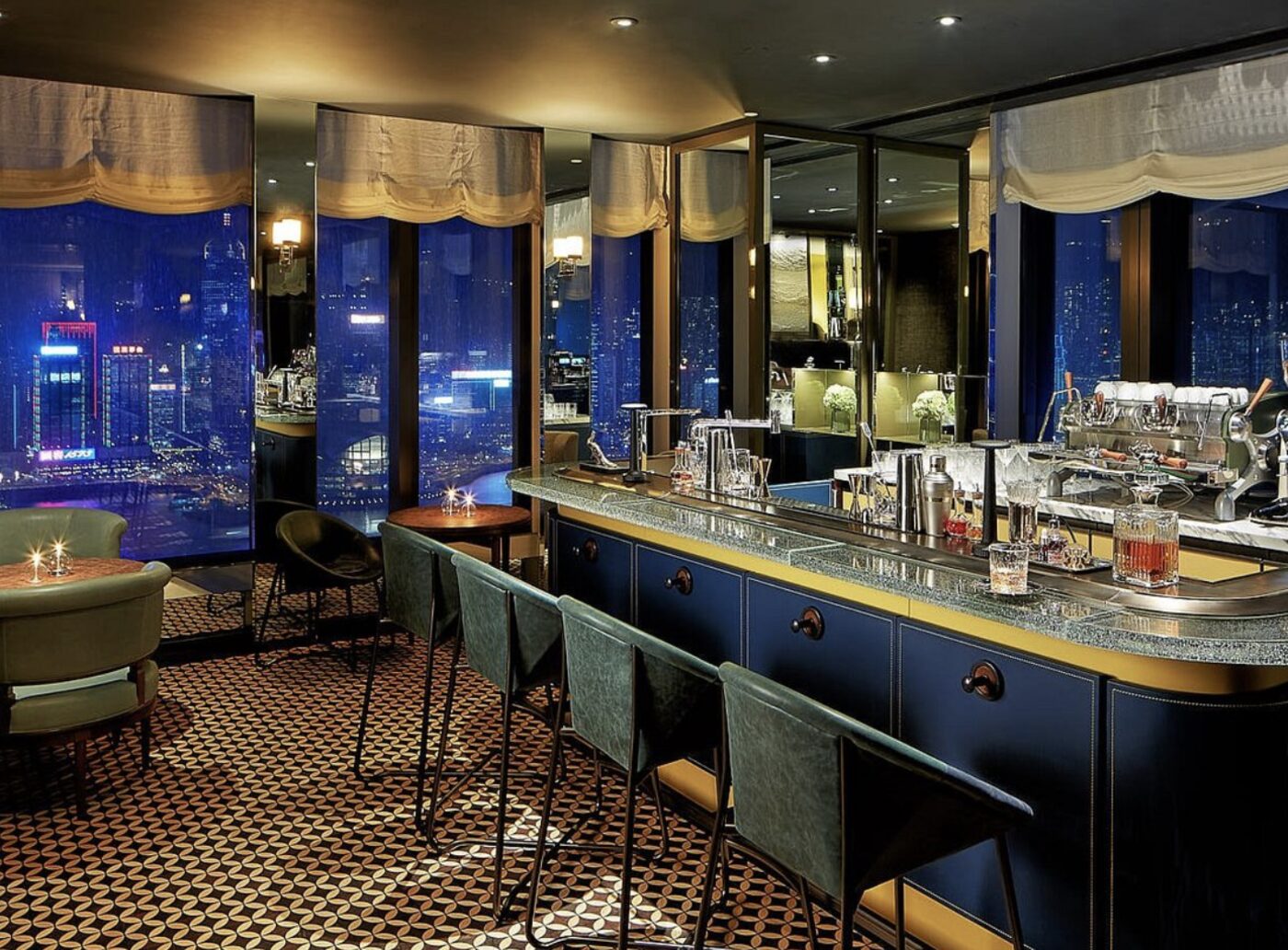 A cocktail bar at Rosewood Hong Kong with floor-to-ceiling night views of the city