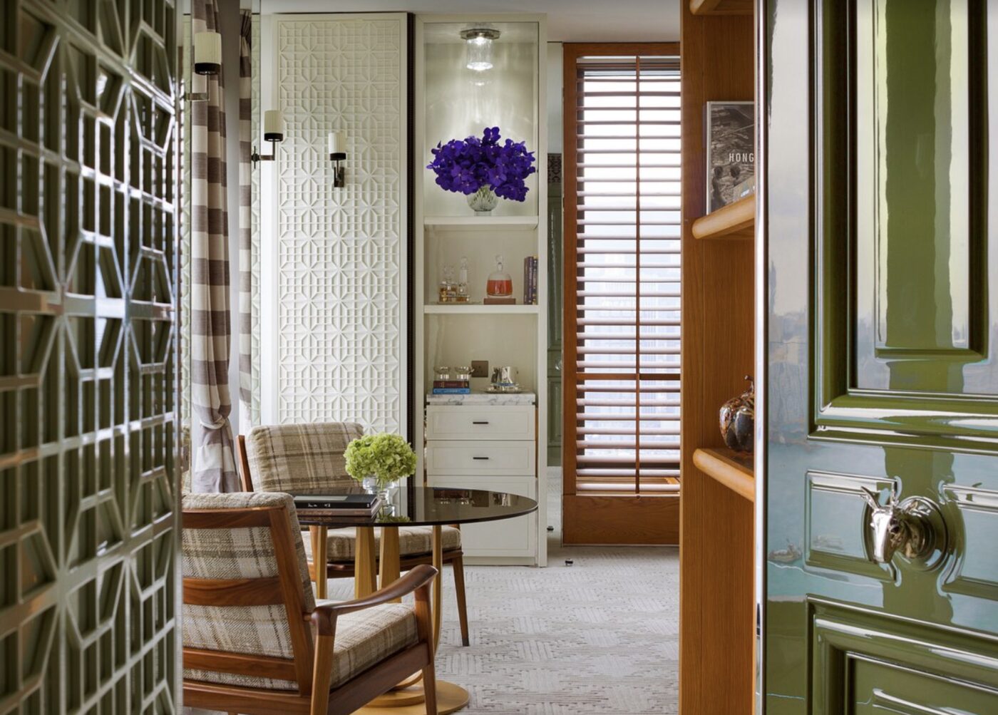 A suite entry hall at Rosewood Hong Kong with a glossy green door and a sitting area beyond