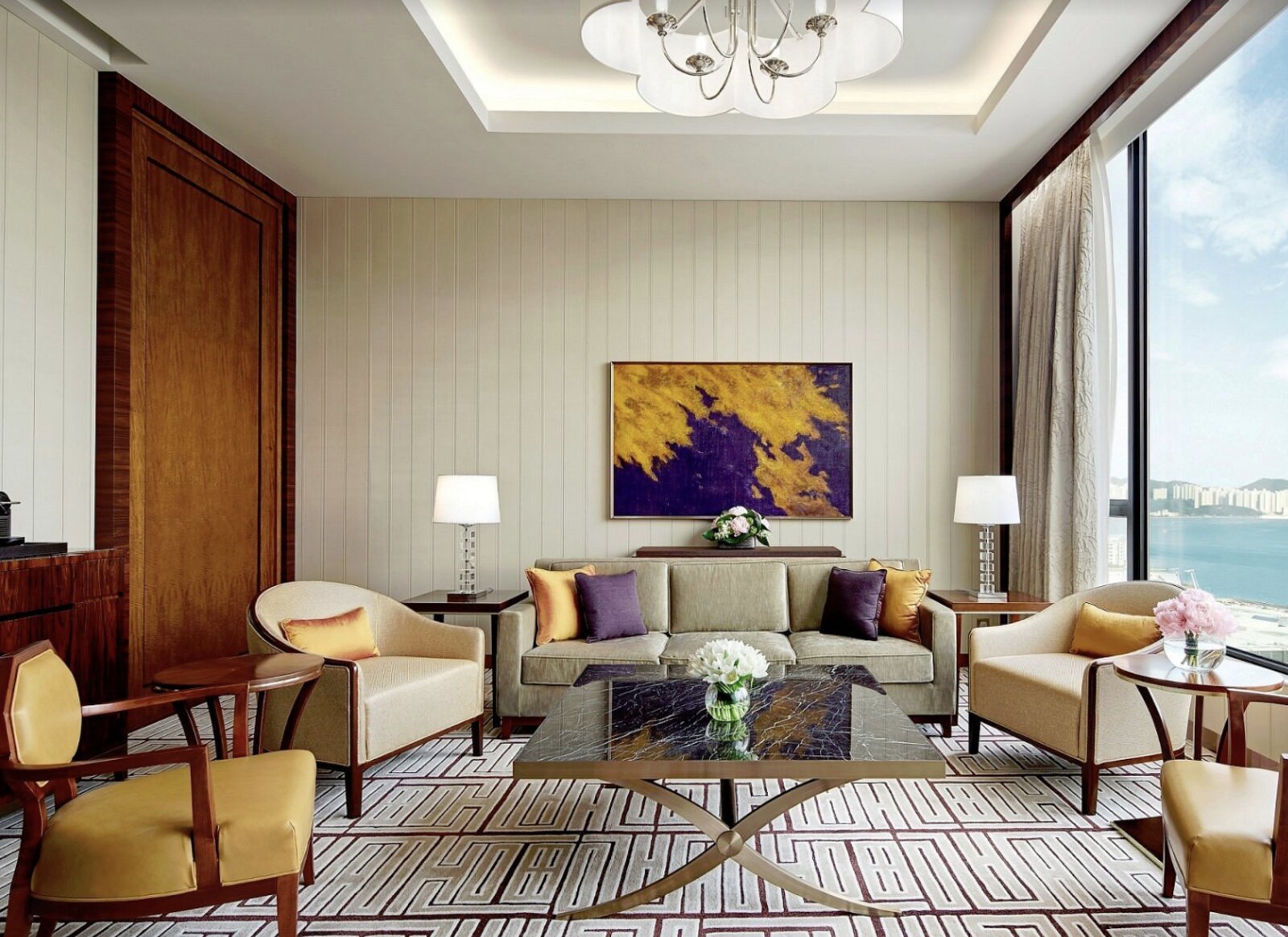 A suite living room at The Royal Garden with plush armchairs and a wide harbour-view window
