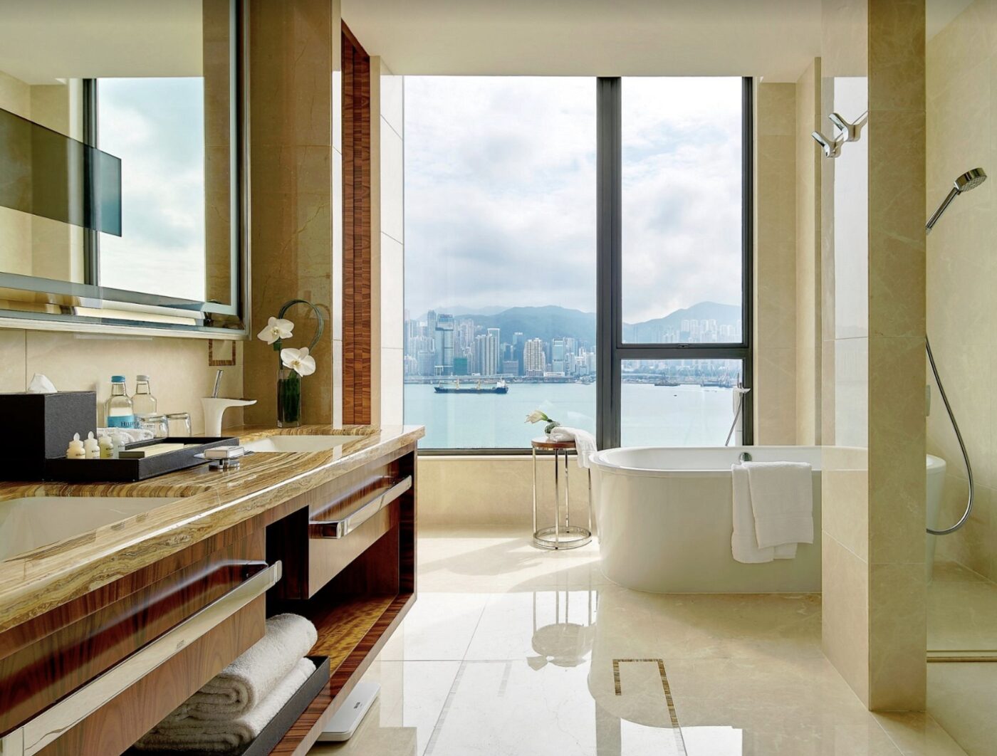 A bathroom at The Royal Garden with a freestanding tub facing floor-to-ceiling windows over Hong Kong Island